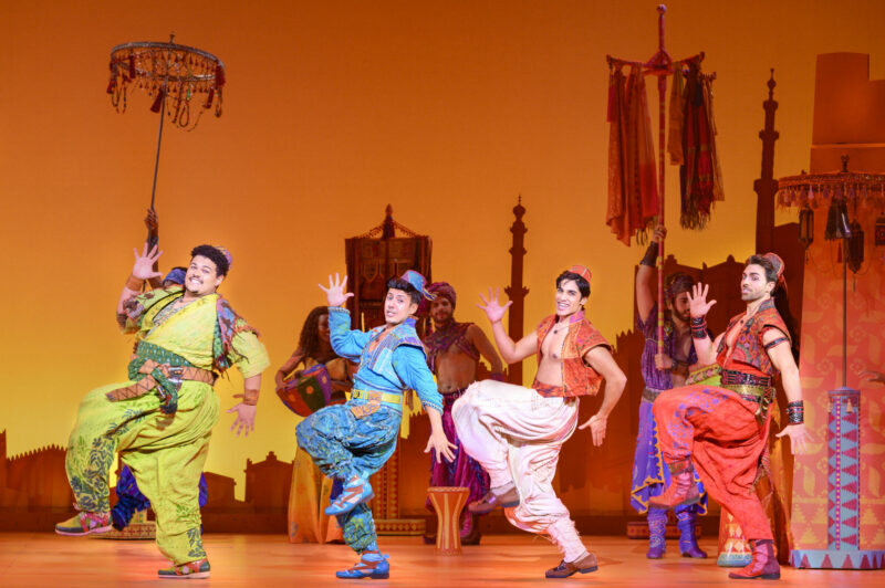 Jake Letts, Ben Chavez, Adi Roy and Colt Prattes in the North American Tour of Aladdin. All are dressed in colorful clothing and dancing.